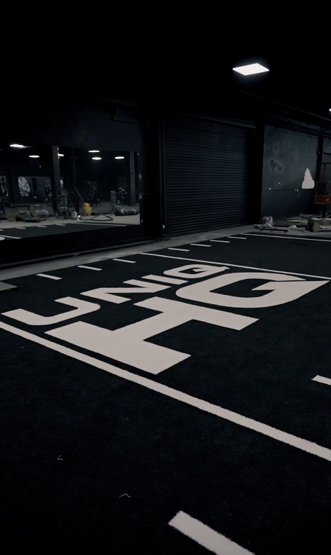 The UNIQ HQ name set into the black training turf inside the gym